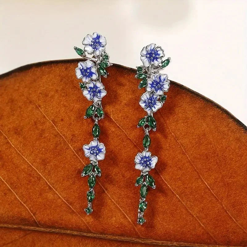 https://cdn.shopify.com/s/files/1/0820/4999/0943/files/glossy-blue-floral-dangling-earrings-345534.webp?v=1712446270