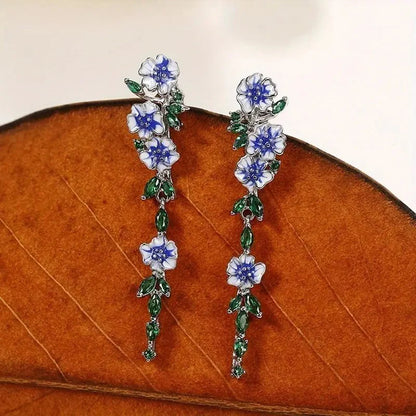 https://cdn.shopify.com/s/files/1/0820/4999/0943/files/glossy-blue-floral-dangling-earrings-345534.webp?v=1712446270